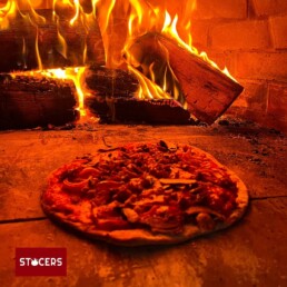 Pizza ligt gaar te bakken in de houtoven.