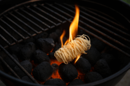 Brandende aanmaakwokkel op gloeiende briketten in een BBQ, ideaal voor snel en veilig vuur aanmaken