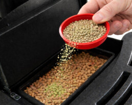 Schoonmaakpellets in pelletkachel via dop van beker